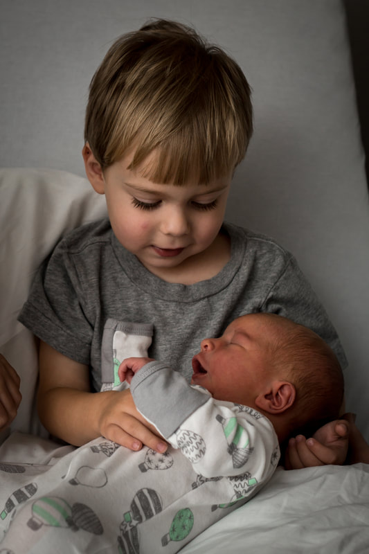 Photo of a toddler meeting his new baby brother in the hospital after birth | Charleston, SC birth photographer