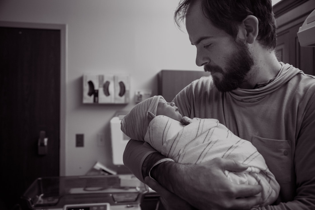 Photo of dad holding his newborn baby girl in the hospital after birth - Charleston, SC birth photography