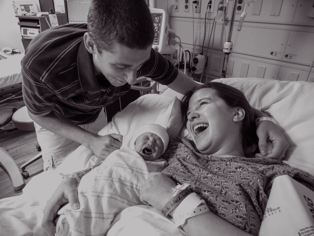 black and white photo of a new mother and father meeting their daughter in recover after a cesarean birth