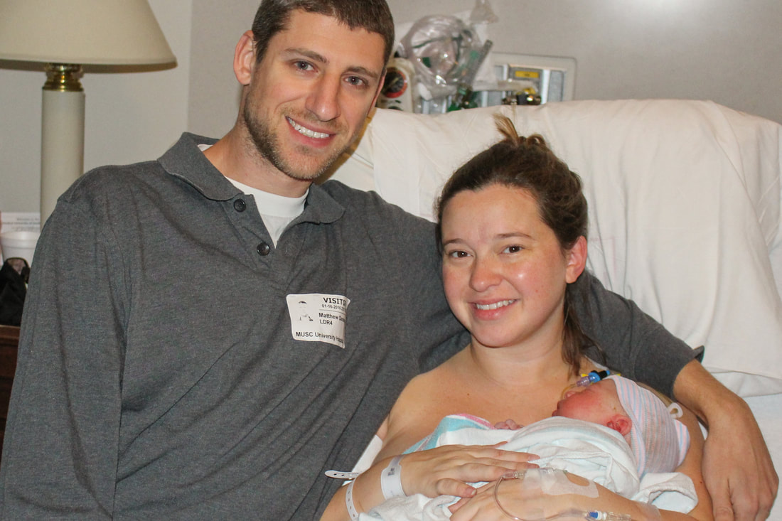 Dad and mom holding newborn baby in hospital after successful VBAC birth in Charleston SC