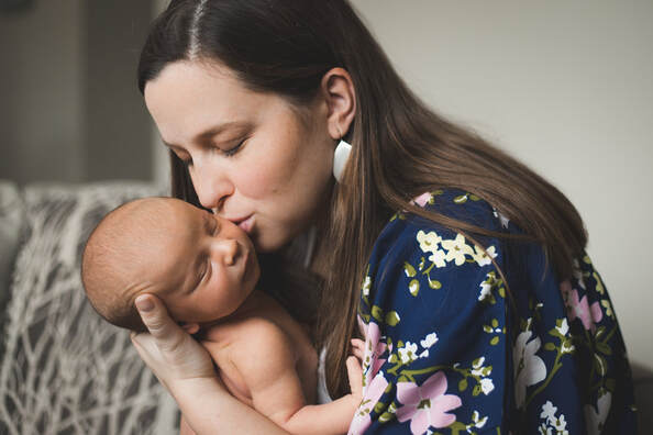 Photo of photographer as a mom kissing her sleeping newborn baby charleston sc