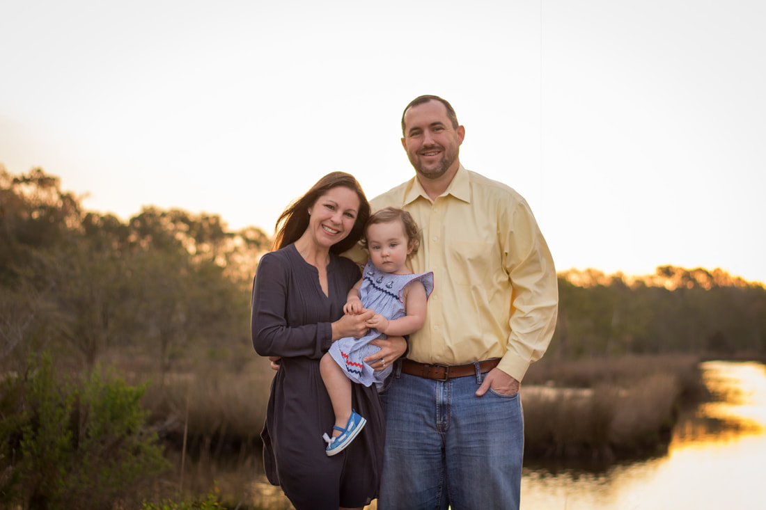 Family portrait of mom, dad, and toddler daughter at sunrise in Charleston, SC