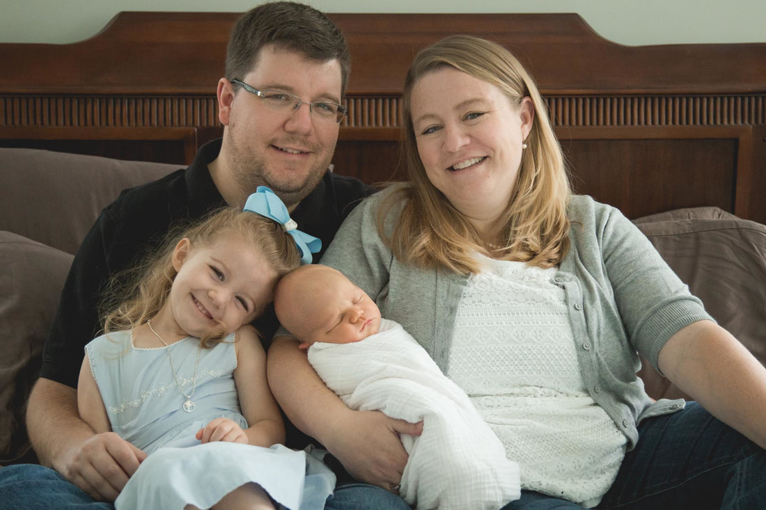 Photo of a family sitting on the bed with their newborn baby during a photo shoot in mt pleasant sc