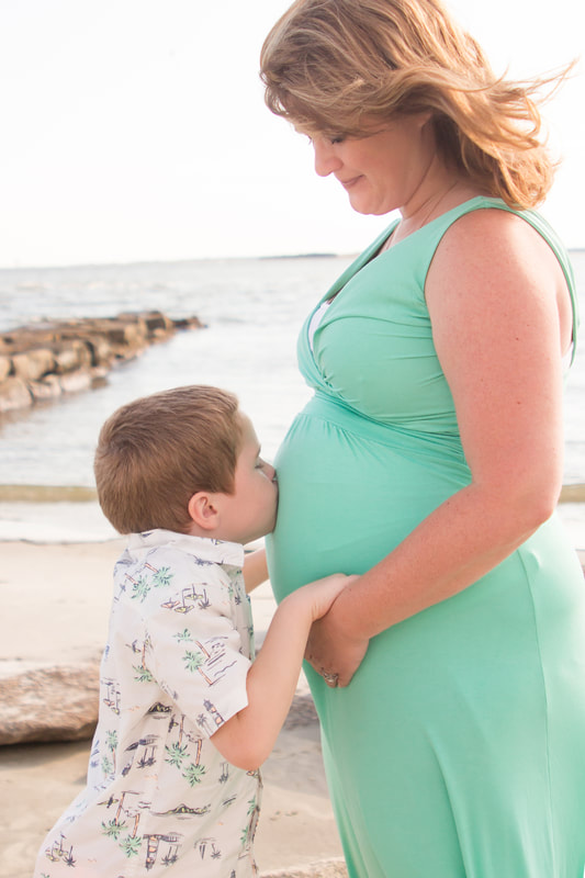 Photo of a young boy kissing his mom's pregnant belly during a beach maternity session in the Lowcountry of South Carolina