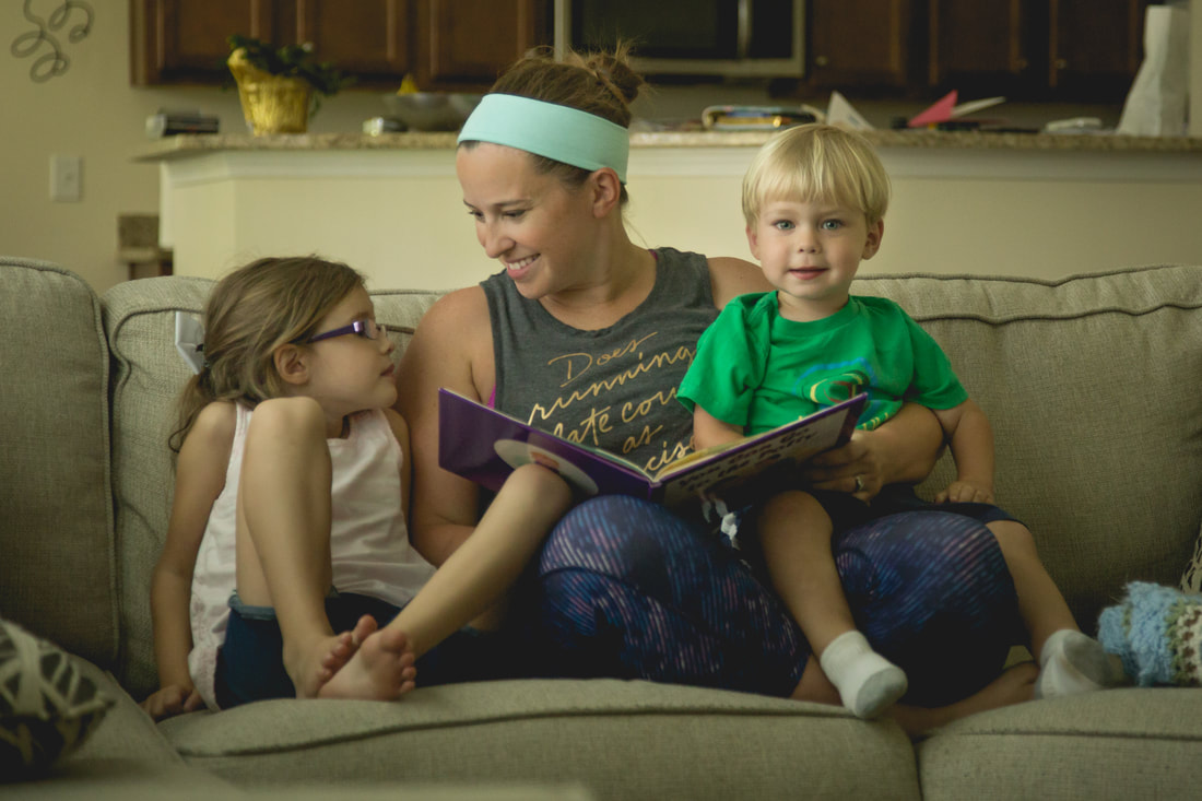 photo of a mom sitting on the couch reading to her two young children - family portrait photography charleston sc