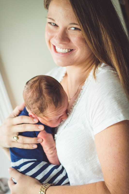 Photo of a smiling mom holding her newborn baby boy - Charleston, SC Lifestyle Newborn Photographer