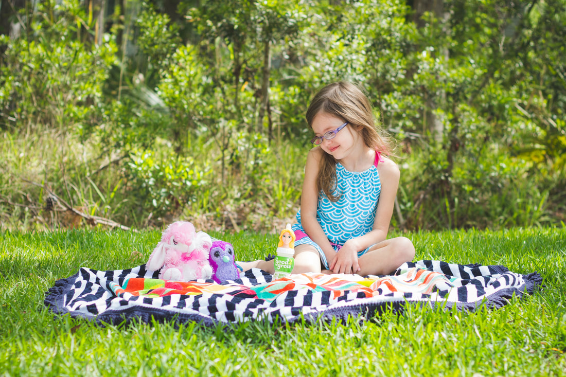 Young girl sitting on a blanket having a picnic with stuffed animals